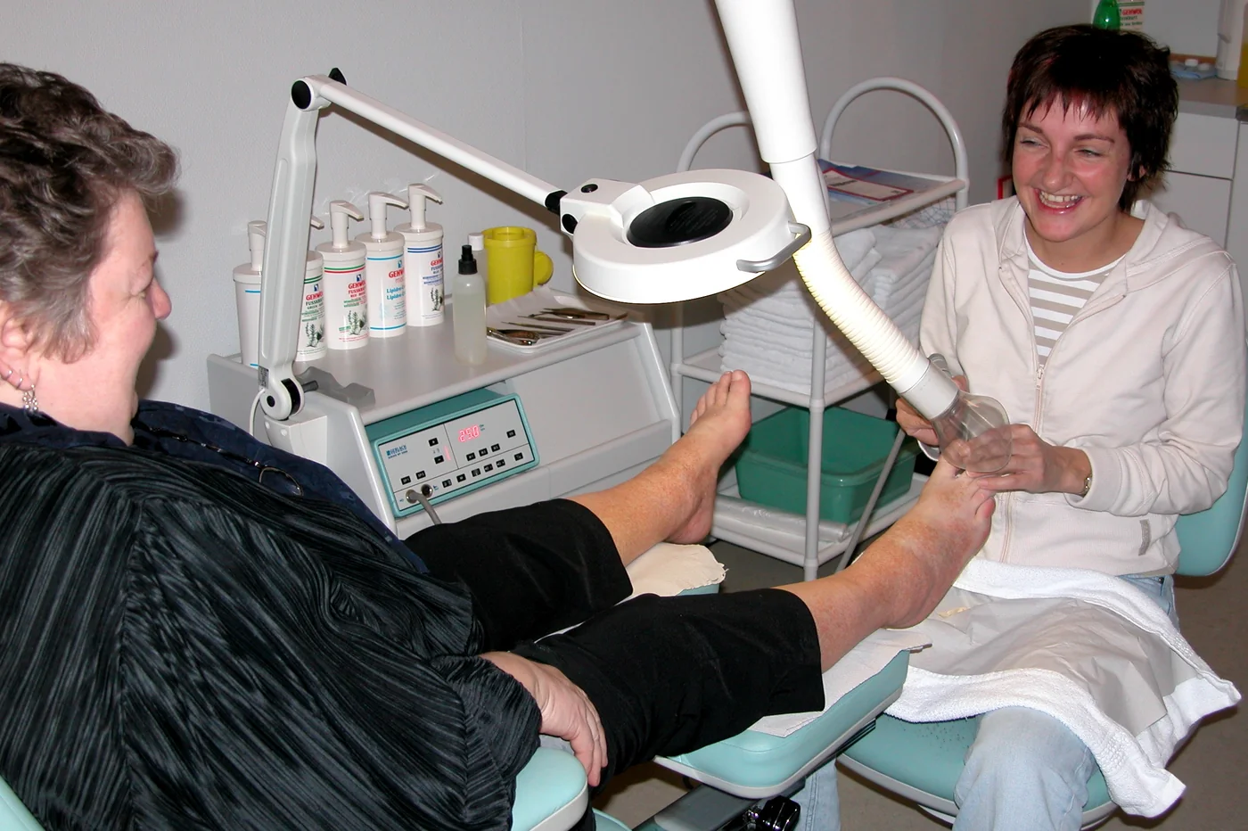 A chiropodist sitting with a patient during a foot-care appointment in a clinic