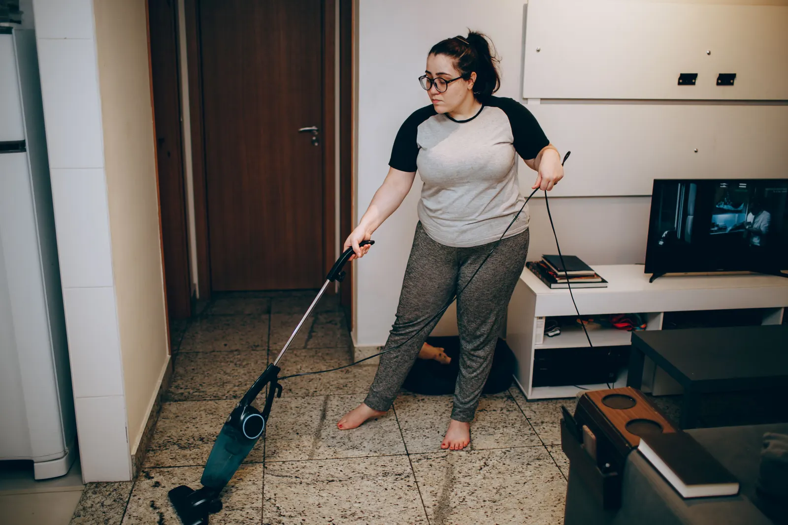 A person vacuuming the floor of a living room at home