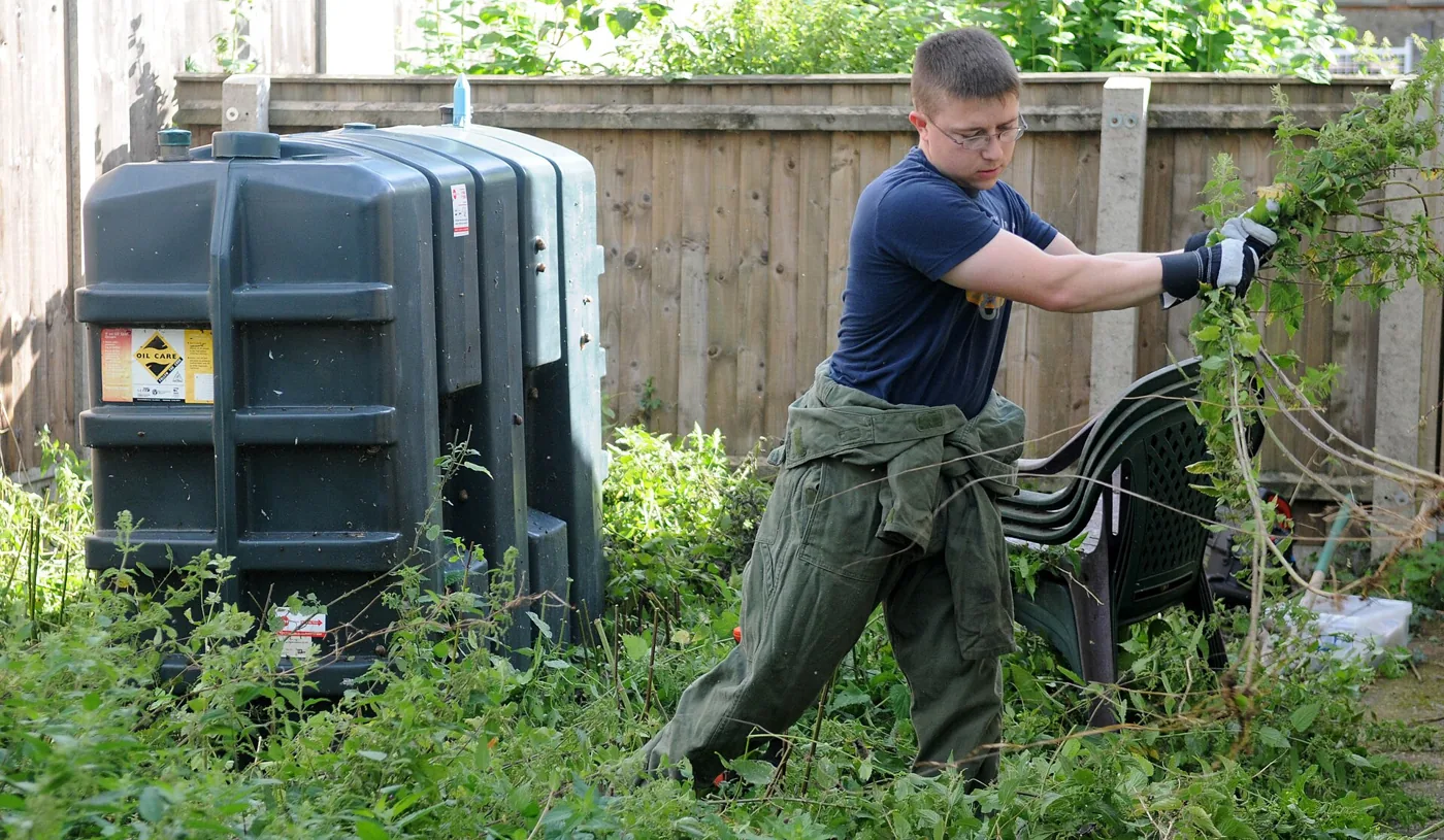 A volunteer cutting back overgrowth in a residential garden in Suffolk
